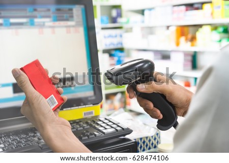 Pharmacist scanning price on a red medicine box with barcode reader in pharmacy store Royalty-Free Stock Photo #628474106