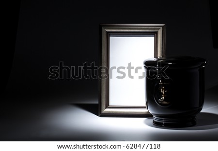 Black evangelical urn with blank mourning frame on dark background
