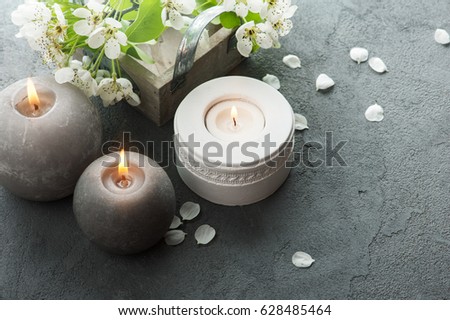 Tree branches with flowers on grey concrete background. Lit candles composition 