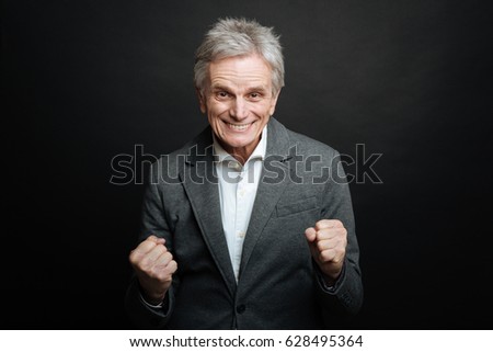Delighted elderly man expressing amusement indoors