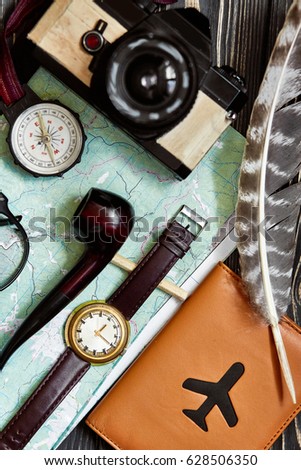 wanderlust and travel concept, hipster flat lay. map passport compass and glasses photo camera pipe on black wooden background top view. planning vacation. space for text
