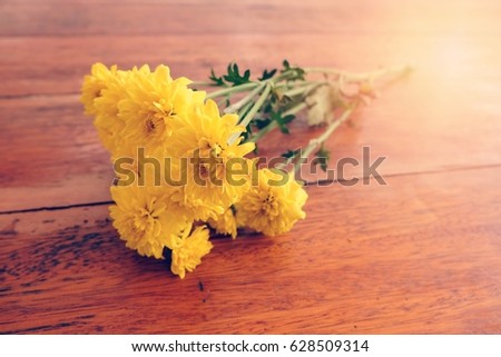The beautiful yellow flower on the wood table