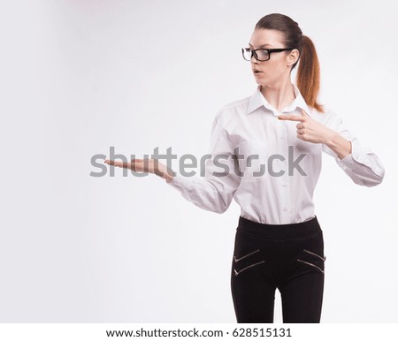 Young happy woman portrait of a confident businesswoman showing presentation, pointing paper placard gray background. 