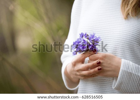 Closeup of woman's hands with small bunch of beautiful blue snowdrops. Spring mood. Girl with flowers.