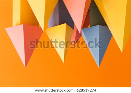 Abstract colorful geometrical shapes background. Three-dimensional prism pyramid objects on orange paper. Yellow blue pink green colored solid figures, soft focus photo