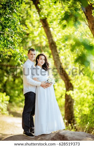 Beautiful pregnant woman with her husband in green garden