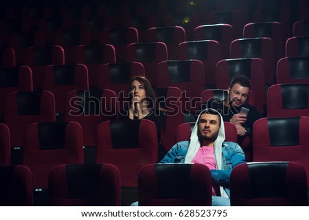 Young adults watching boring film in movie theater