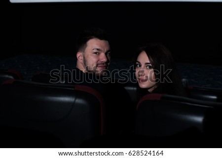 Young romantic couple sitting in movie theater.