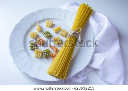 Top view. A plate of raw pasta: macarons shaped of paris sightseings (Notre Dame de Paris, Triumphal Arch and Eifel Tower) made of vegetables at white plate at wooden background