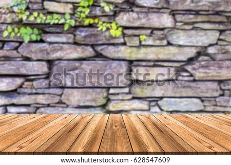 Empty wooden board table in front of blurred background. Perspective of stone wall with natural texture and pattern can be used for display or montage products or advertise text