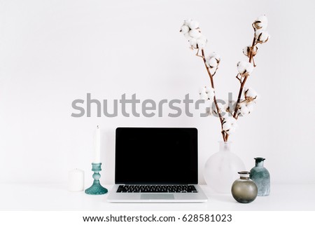 Blogger or freelancer workspace with front view of laptop with black blank screen at white background. Minimalistic decorated home office desk.