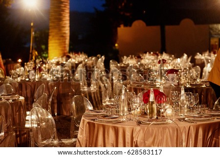 Street lamps shine over round dinner tables rich served for wedding ceremony