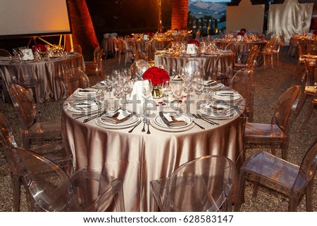 Silver cloth covers round table served with sparkling glassware and white plates