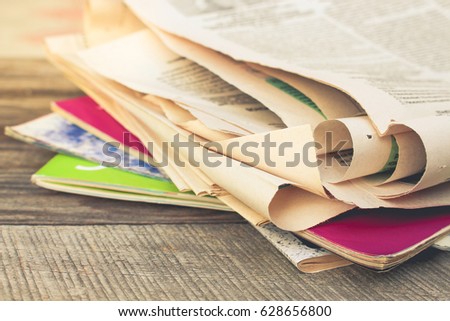 Newspapers and magazines on old wood background. Toned image. 