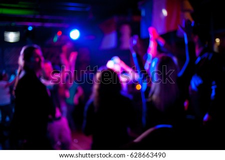 Silhouettes of dancing people in a club in front of bright scenic lights concept of disco, night life. Blurred people are dancing in a night club with original bokeh lights in the background.