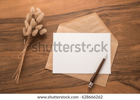 Dry flowers, envelope and pen on a wooden background
