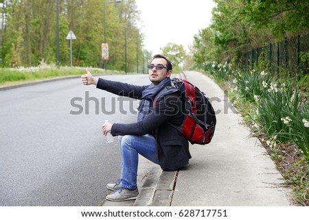 Man tourists hitchhiking along a road
