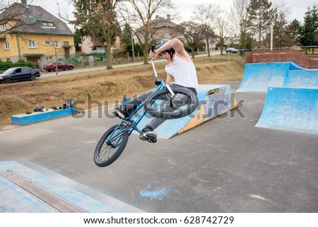Young boy jumps on a bmx in a skate park.