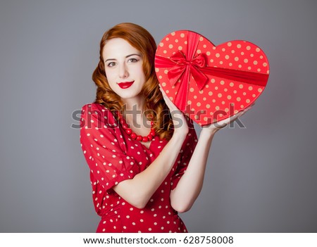 portrait of beautiful young woman with heart shaped gift on the wonderful grey studio background