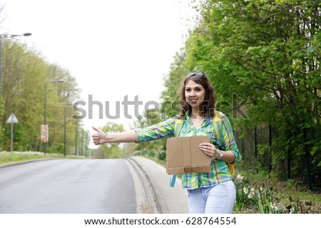  young girl tourists hitchhiking along a road