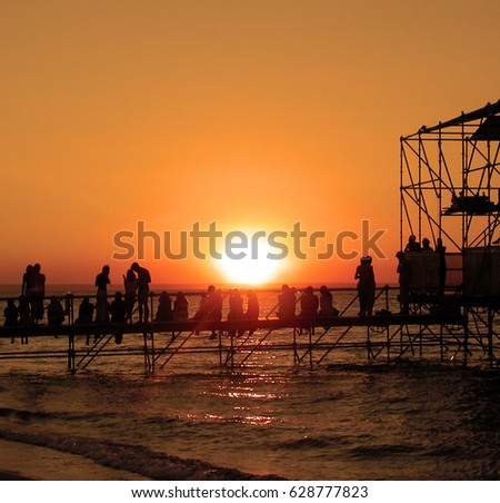 Group of young people on the beach watching the sunset during music festival