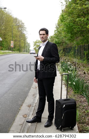 Handsome business man standing on a highway and catching a car