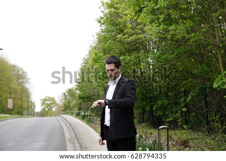 Handsome business man standing on a highway and catching a car