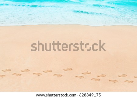 Soft wave of Blue ocean on sandy Beach with footprint. Abstract natural Background.