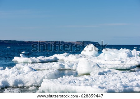 Large ice flow of melting icebergs pressed up against the shore 