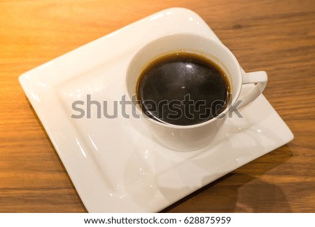 Black coffee in white glazed corner on a wooden floor.
