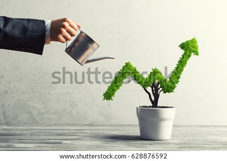 Hand of woman watering small plant in pot shaped like growing graph Royalty-Free Stock Photo #628876592