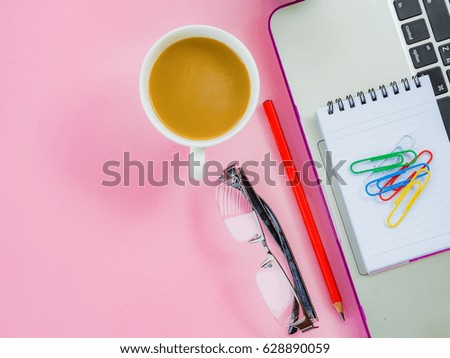 Flat lay, top view office table desk frame. feminine desk workspace with office accessories including laptop, note book, white pen, coffee cup, pink glasses,earphone and flower on pink background.