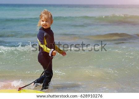Young surfer girl with bodyboard walks along beach sea surf - Stock image