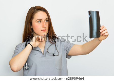 Young female doctor with stethoscope looking at the x-ray picture on white background