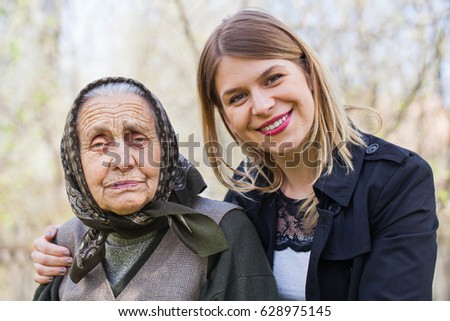 Picture of a sick elderly woman posing with her happy caretaker outdoor