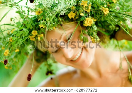 Young happy girl in wreath of grasses and flowers. Summer day in a meadow. Summer day in the forest. Selective focus