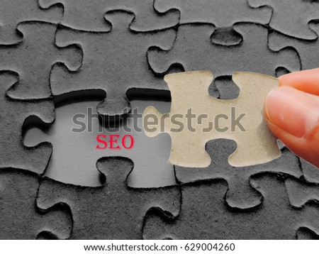 Hand holding a piece missing puzzle,"SEO" text puzzle want to complete it - business and finance concept.          