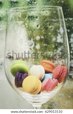 Cake macaron or macaroon in big wine glass on wet window glass side background, colorful almond cookies, pastel colors, vintage card, side view.My afternoon tea lovers.Happy and Lonely season.