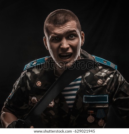a photo of a guy in military clothes. holding a machete
