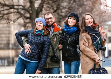 A team of four happy friends students hugs and laughs in the park of a European city in the winter, travel concept