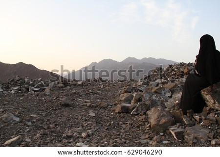 a muslim women photographer sitting in mountain area