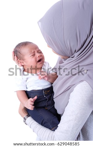 Young mother holding her newborn child. Mom nursing baby. Woman and new born boy relax in a white studio. Nursery interior. Mother breast feeding baby. Family at home