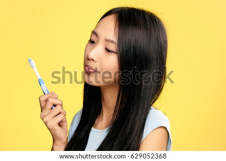   Brunette girl with toothbrush in her hand brushes teeth of Korean woman                             