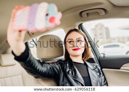 Young smiling gril making selfie portrait sitting in the car