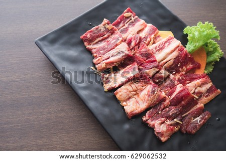 FOOD : fresh raw meat on black plate serving with vegetable on wooden table