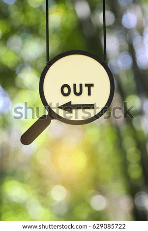 An "Out" with arrow magnifying glass sign against blur light and bogey background