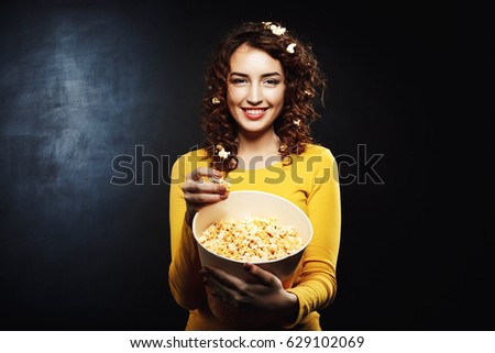 Funny girl with popcorn on hair smiling and looking straight 