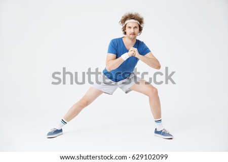 Guy in retro sport suit doing stretching exercises. White background