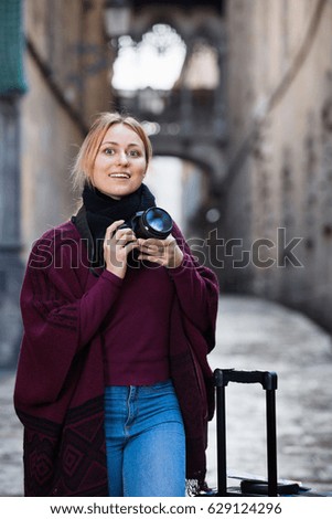 Charming happy woman looking curious and taking pictures outdoors