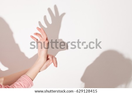 child plays with a parent in the theater of shadows on a white wall